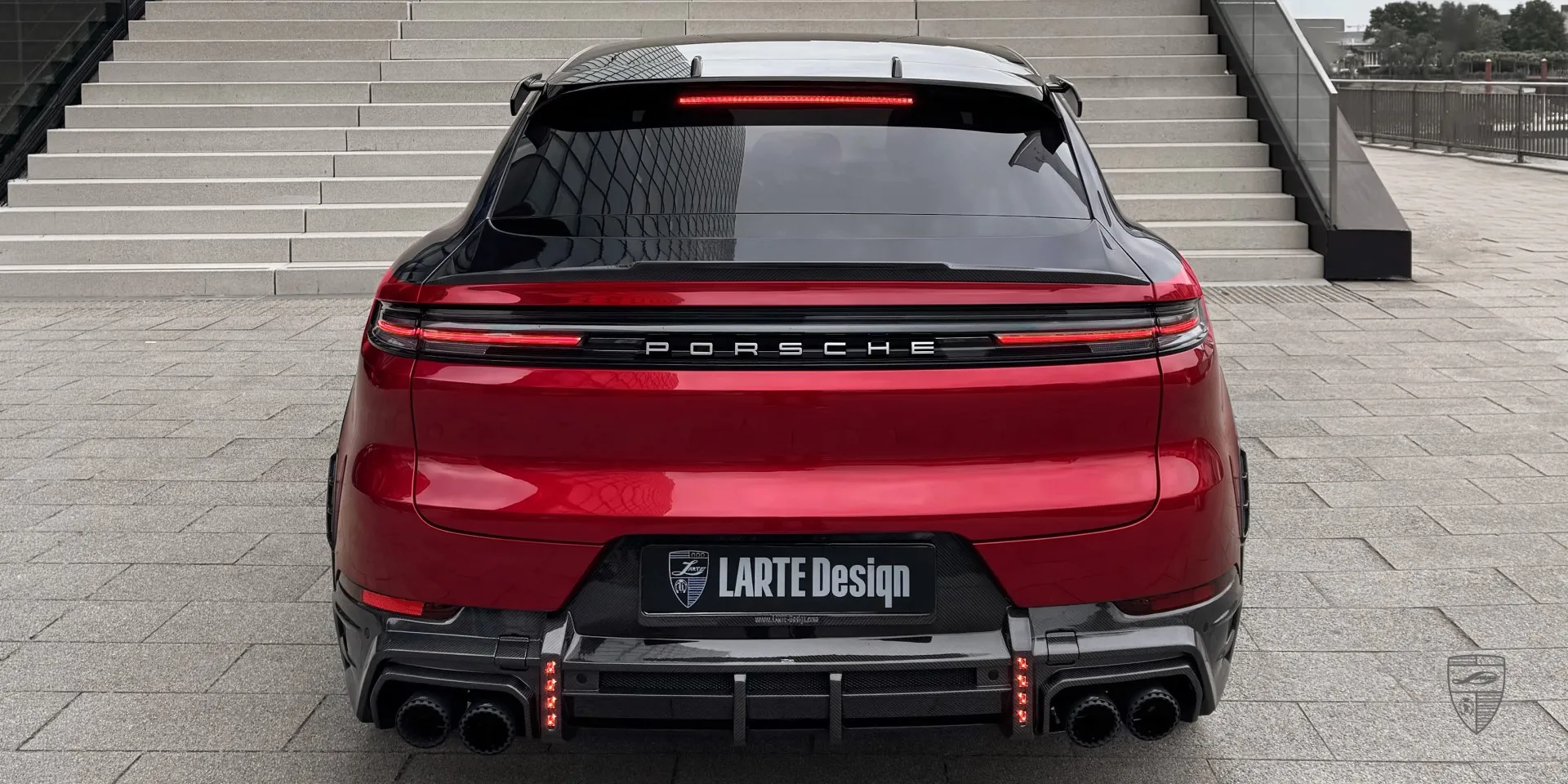Красный Porsche Cayenne Coupe в обвесе в городской панораме