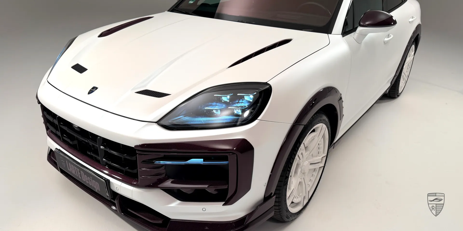 Вид с заниженной подвеской: белый Porsche Cayenne с тюнинг‑комплектом кузова и розовым dry carbon